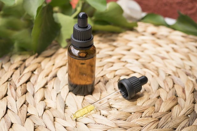 CBD oil sitting on top of a woven basket.